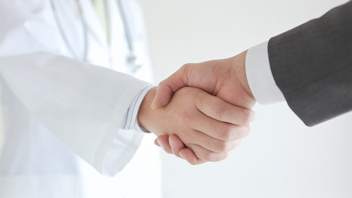 Doctor and person in a suit shaking hands