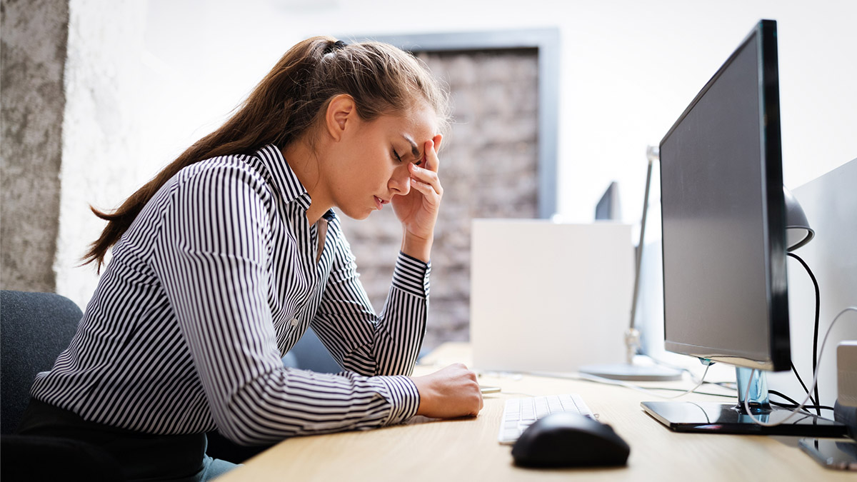 Woman sitting at desk resting head on hand