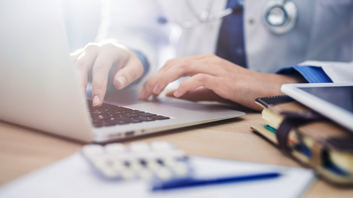 Close-up of a doctor typing on a laptop